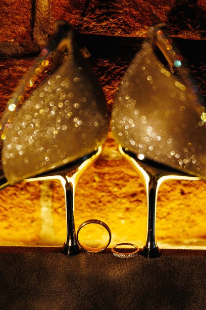 黑色背景上的金色婚戒，映衬着婚鞋的倒影。高质量照片。图片下载