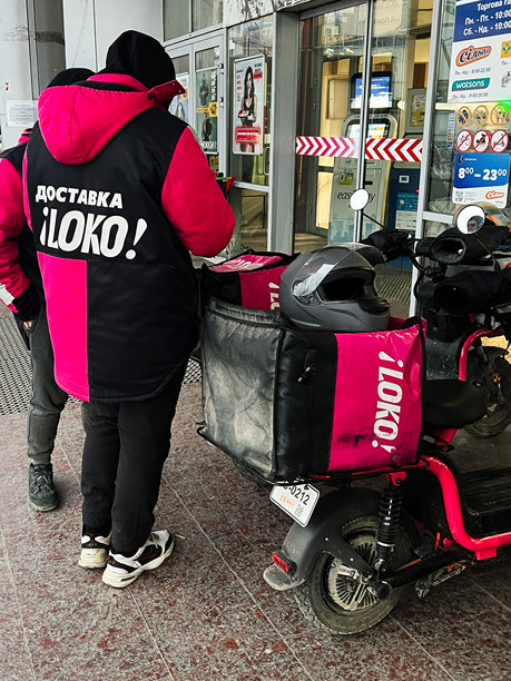 冬季城市中骑着品牌电动车的外卖员工图片下载