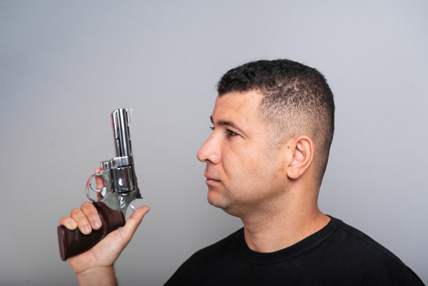 身穿黑色衬衫和牛仔裤的帅气男子手持枪械。图片下载