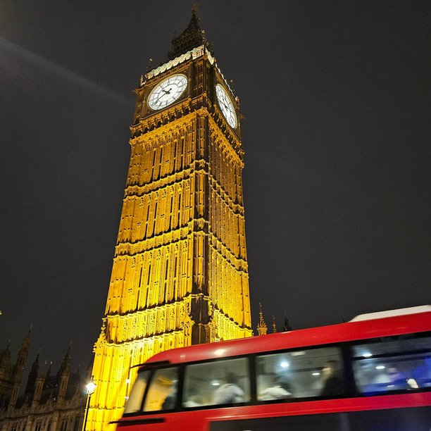 夜间拍摄的照片，仰望大本钟和一辆在威斯敏斯特地铁站旁驶过的伦敦红色公交车，拍摄于十二月。图片下载