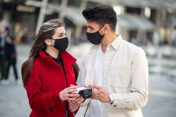 一对戴着防护口罩的情侣在疫情期间查看相机中的照片图片下载