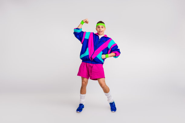 充满活力的年轻男子穿着鲜艳的复古运动服，自信地摆姿势，拍摄动态健身照片，背景为白色。图片下载