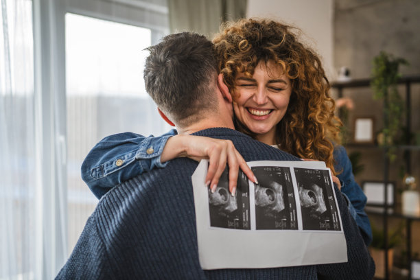 拥抱的情侣肖像，手持超声波孕妇宝宝照片图片下载