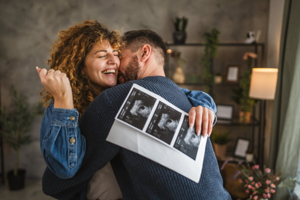 拥抱的情侣肖像，手持超声波孕妇宝宝照片图片下载