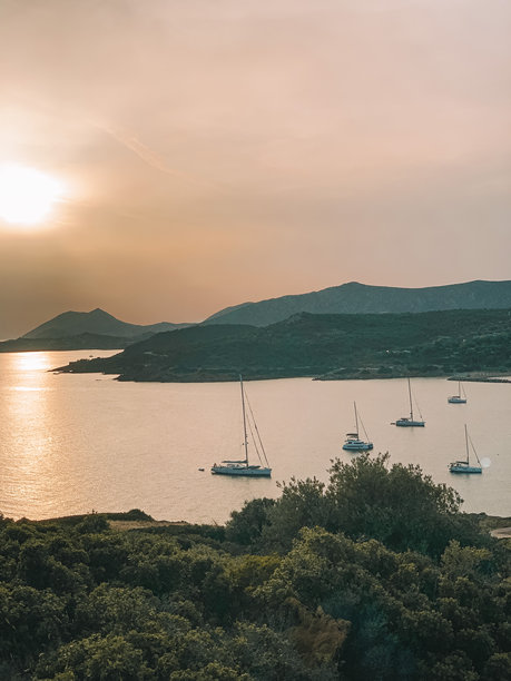 宁静的日落时分Cape Sounion的照片，船只轻轻漂浮在爱琴海上，天空被鲜艳的橙色、粉色和紫色渲染。图片下载
