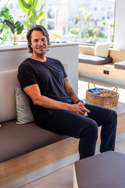 一个男人坐在沙发上，旁边有一个装满书籍的篮子。照片留有空白空间。图片下载