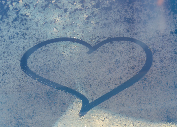 情人节概念：冰冻汽车挡风玻璃上的手绘心形图案。汽车挡风玻璃上的手绘心形。爱的象征。图片下载