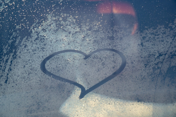 情人节概念：冰冻汽车挡风玻璃上的手绘心形图案。汽车挡风玻璃上的手绘心形。爱的象征。图片下载