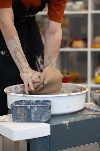 一个男人的手在陶艺轮上打破陶瓷花瓶的特写。陶瓷学校。竖版照片。图片下载