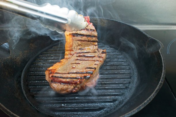 一系列展示在铸铁煎锅中煎制西冷牛排的方法的图片。图片下载