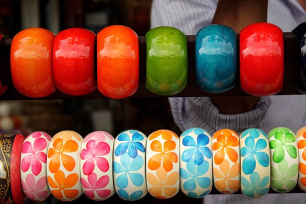 在泰国曼谷的乍都乍周末市场展示的色彩斑斓的手绘木手镯和手链特写，带有花卉和生动的设计图案。图片下载