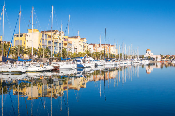 法国奥克西塔尼地区格吕桑港的帆船与建筑在深蓝色天空下的照片图片下载