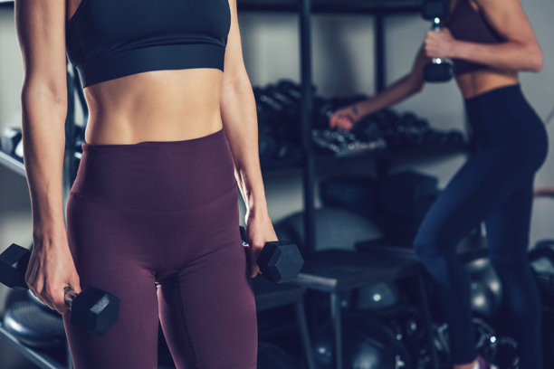 女性腹肌和手握哑铃的特写照片图片下载