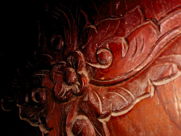 精美的木雕，表面为深红色，呈现出旋转的花卉图案。这张照片突显了传统木工的艺术性和工艺水平。图片下载