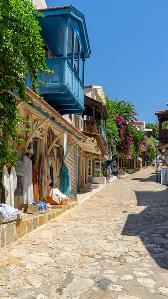 土耳其卡什的商店和地中海风格的房屋，木质阳台被绿色植物和九重葛环绕。漫步在城市中。竖版图片图片下载