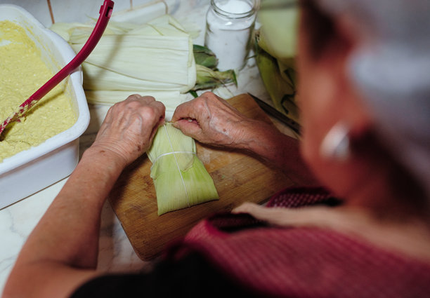 一个人在智利的家中准备用玉米棒制作的玉米饼，以及一个人在吃玉米饼的照片图片下载