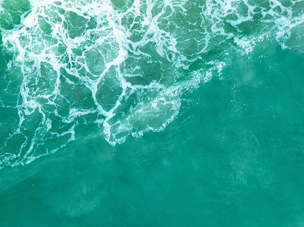俯视图的碧绿色暴风海洋波浪，海面上有白色泡沫，海水溅起水花和泡沫，波浪背景的顶视图，自然背景照片，海洋纹理，波浪柔焦效果。图片下载