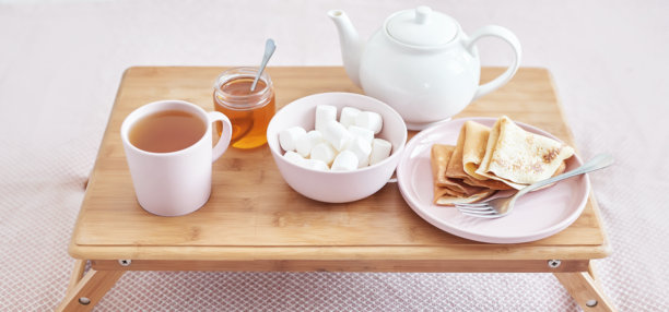 Breakfast in bed in hotel room. Accommodation. Breakfast in bed with tea cup with pancakes on tray on bed background top view. Copy Space. Romantic valentine's day breakfast. Cozy breakfast Maslenitsa图片下载