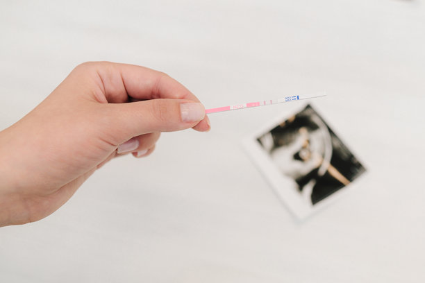 白色背景上的积极怀孕测试和婴儿超声波照片。未来的母亲手持显示阳性结果的怀孕测试。图片下载