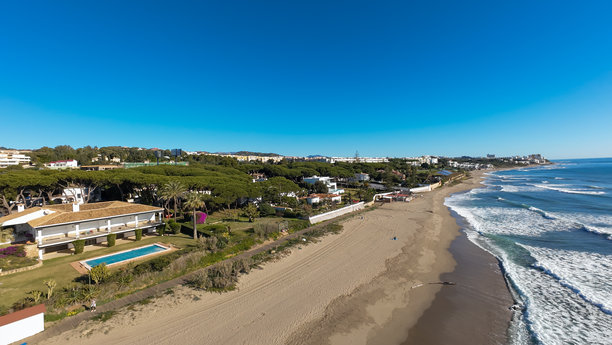 西班牙米哈斯的卡拉霍达小镇美丽海滩的航拍照片，展示了阳光明媚的日子里沙滩和前方公寓的全景。图片下载