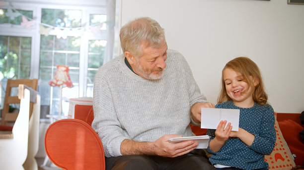 祖父与孙女坐在家里的沙发上一起看照片图片下载