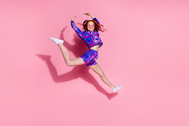 积极女孩在柔和色彩背景下跳跃，进行体操、芭蕾和杂技表演的照片图片下载