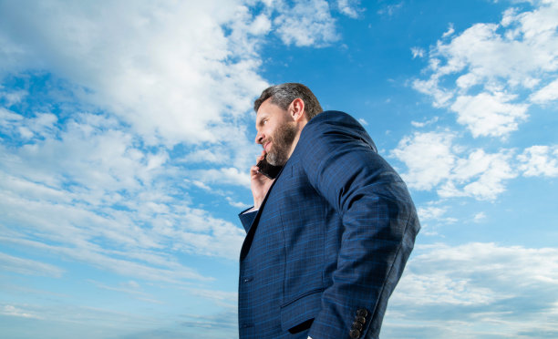 男人在户外打电话，穿着西装。男人打电话的照片。图片下载