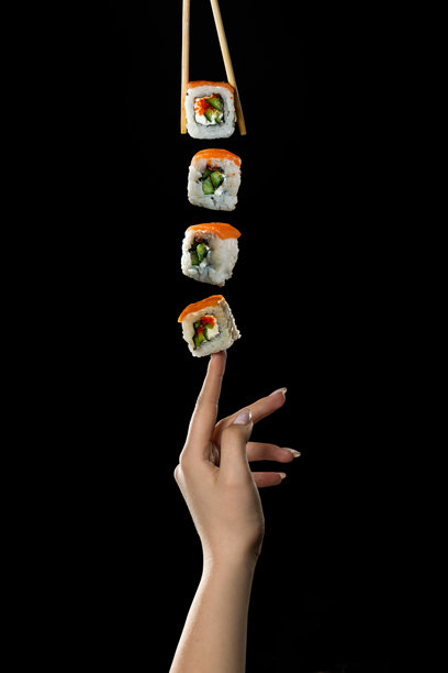 创意照片：黑色背景下，手指悬浮着寿司卷、海苔棒和芝麻，适合餐厅菜单。图片下载