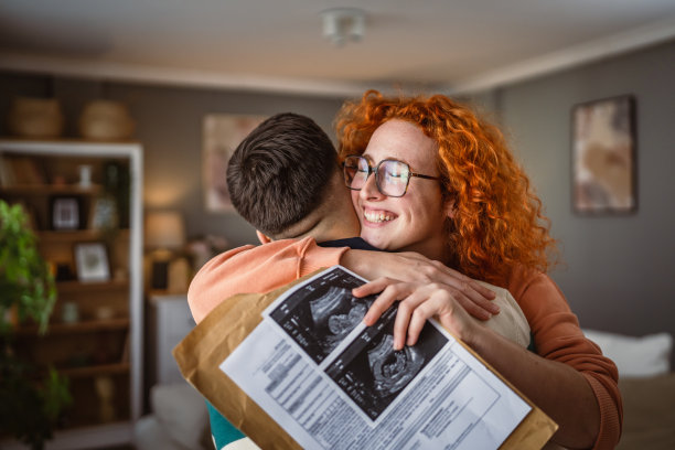 拥抱的情侣手持超声波孕妇的宝宝照片图片下载