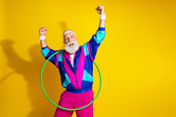穿着复古运动服的搞笑老年运动员在黄色背景下旋转呼啦圈，赢得胜利的照片肖像横幅图片下载