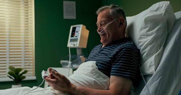 躺在医院病床上的老人，手握手机，翻阅家庭照片，与亲人分享回忆。图片下载