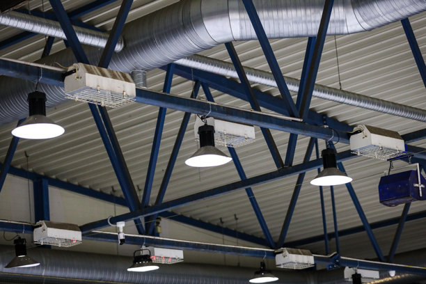 黑暗的老冰球场天花板结构细节，悬挂着灯光和音响扬声器。照片拍摄于昏暗的环境中。图片下载