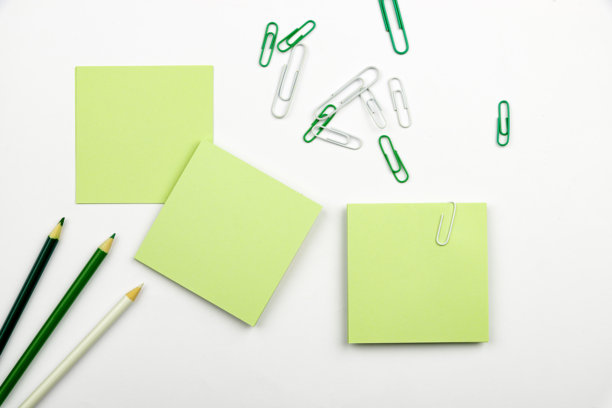 多种办公文具集合照片，包括钢笔、铅笔、记事本、笔记本、尺子、订书机、剪刀、夹子、回形针、文件夹，摆放在桌子上。图片下载