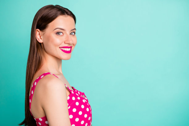 特写照片，迷人的女士微笑着，穿着波点服装，背景为青绿色。图片下载