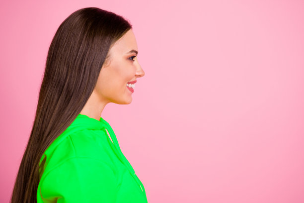 穿着鲜艳黄色毛衣的快乐有趣可爱的女友侧身站立，背景为柔和的色彩，留白照片。图片下载