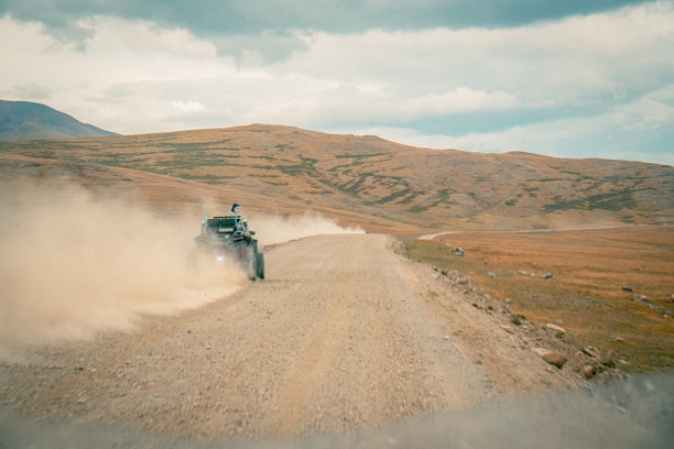 在阿尔泰沙漠的越野旅行。山地风景，丘陵与美丽的蓝天和背景中的云朵。越野车在尘土飞扬的泥土路上行驶。阿尔泰共和国的积极休闲活动。图片下载