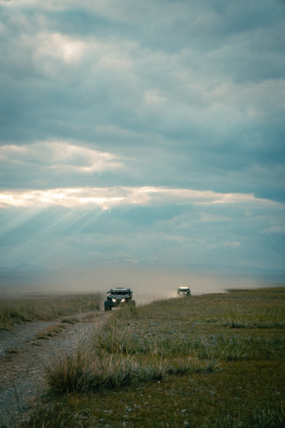 在阿尔泰沙漠的越野旅行。山地风景，丘陵与美丽的蓝天和背景中的云朵。越野车在尘土飞扬的泥土路上行驶。阿尔泰共和国的积极休闲活动。图片下载