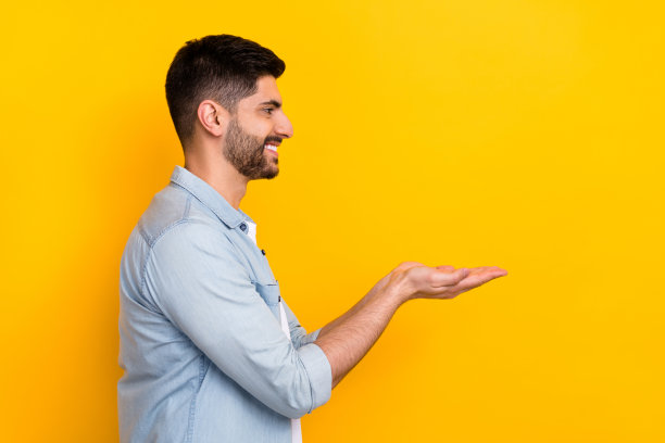 年轻商人侧面照片，面向空旷空间，展示公司新产品，背景为黄色。图片下载