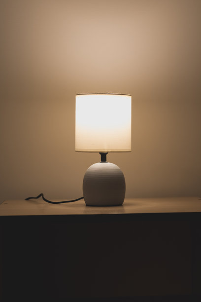 现代床头灯。温暖的床边灯光适合阅读书籍。竖版照片。图片下载