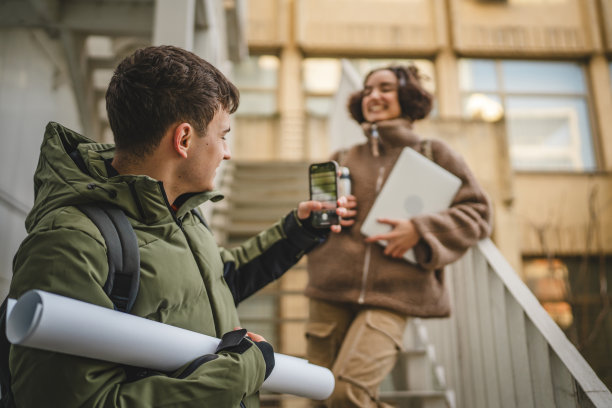 年轻男子在楼梯上用手机拍摄年轻女子的照片图片下载