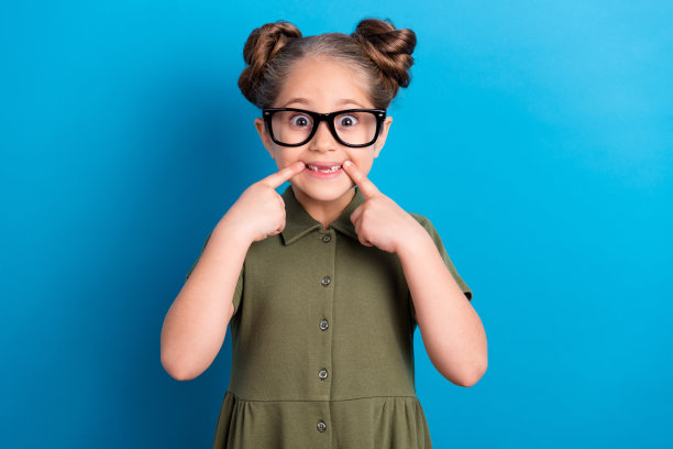 微笑的可爱学生推荐牙医，穿着T恤，背景色彩明亮，适合牙科治疗诊所的照片。图片下载