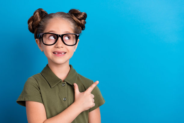 可爱的学生指向空白处的照片，穿着T恤，背景为蓝色，适合9月1日促销活动。图片下载