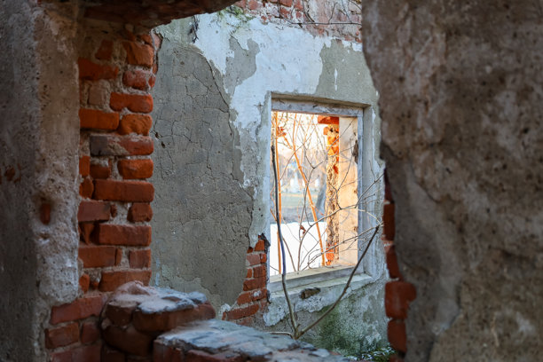 这张照片展示了一座建筑废墟中的窗户。建筑的墙壁部分被毁坏，砖石和残留的灰泥可见。图片下载