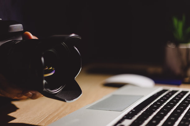 专业摄影师在现代家居工作空间旁边调整相机镜头，周围是创意设备，准备进行照片编辑会话。图片下载