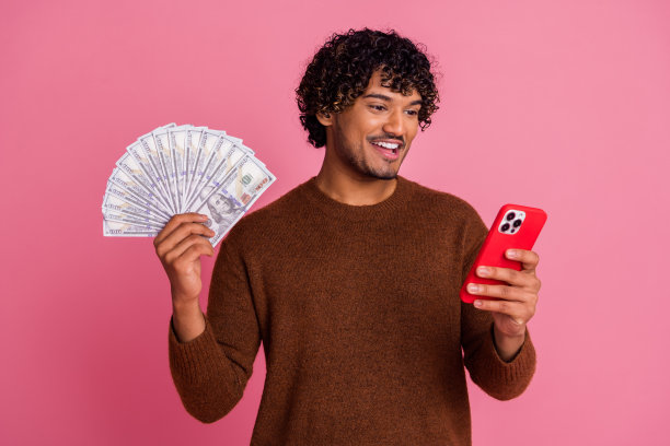 穿着时尚衣服的快乐积极的男人在粉色背景上赚取金钱的照片图片下载