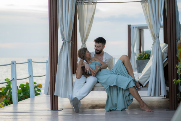 微笑的情侣在阳光躺椅上放松，享受夏季假期 - 股票照片图片下载