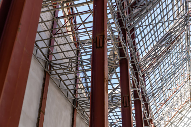 工地上正在建设的巨大钢屋顶框架结构细节的仰视角度照片。图片下载