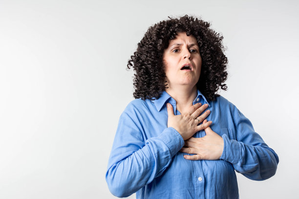 胸部压力。特写照片显示一位感到压力的女性，正在触摸她的心脏区域，面露痛苦。图片下载