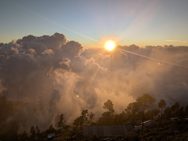 从危地马拉安提瓜附近的阿卡滕戈火山顶上拍摄的无人机航拍照片，展示了日出时分云层之上的美丽景象。图片下载
