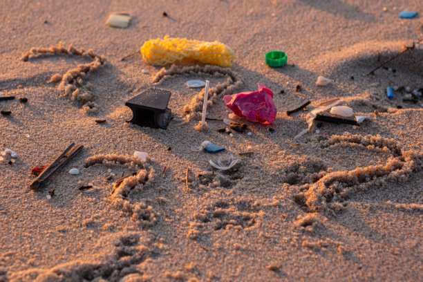 海滩上的塑料垃圾。环境受到塑料污染。被废物污染的海洋沙滩。沙子上画着一个问号。特写照片。图片下载